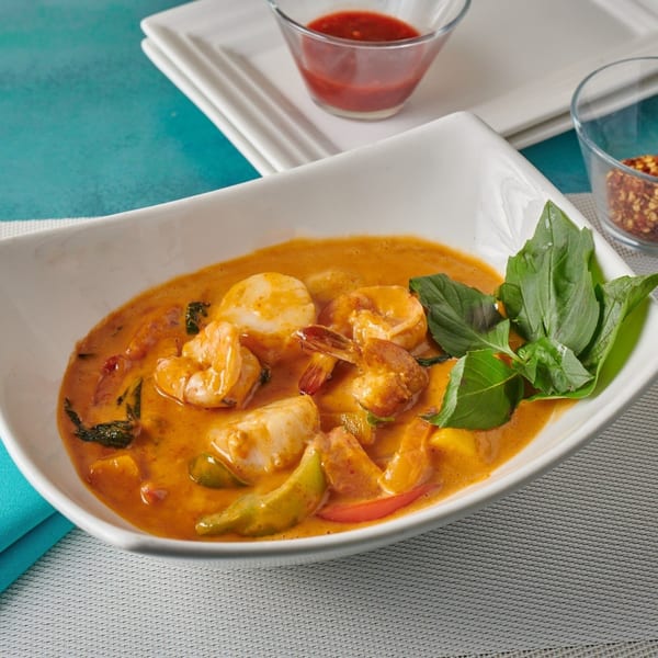 Blue Mango's Thai red curry with shrimp, scallops, and vegetables, garnished with fresh basil.