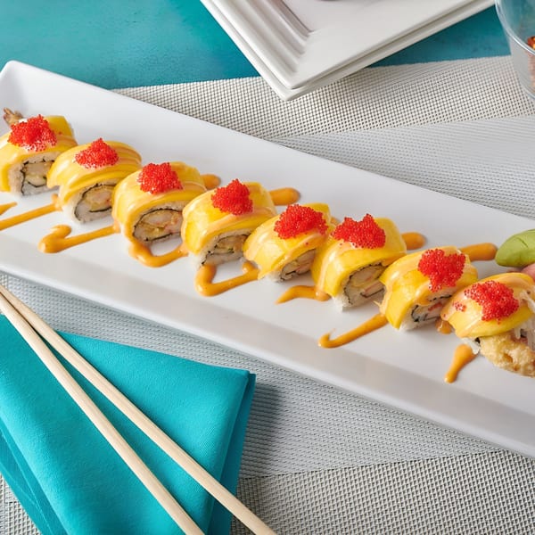 Blue Mango's mango sushi rolls with red tobiko and orange sauce on a white platter with chopsticks.